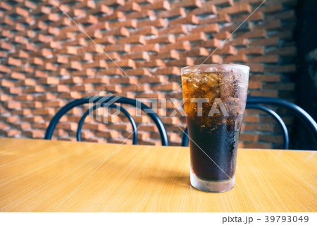 A glass of cola with ice on the table. 39793049
