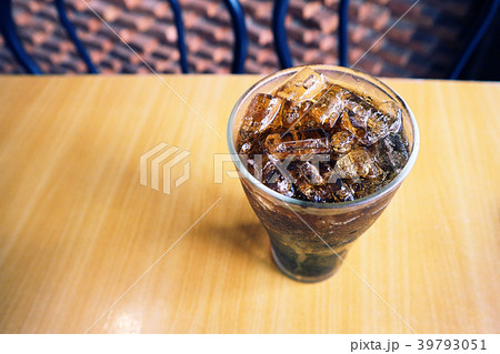 A glass of cola with ice on the table. 39793051