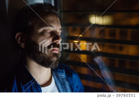 A man slepping by the window at home at night. 39793551