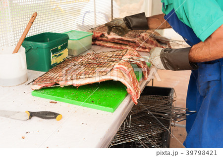 Cook prepares the meat to roast on the grill. Cook prepares the meat to roast on the grill. 39798421