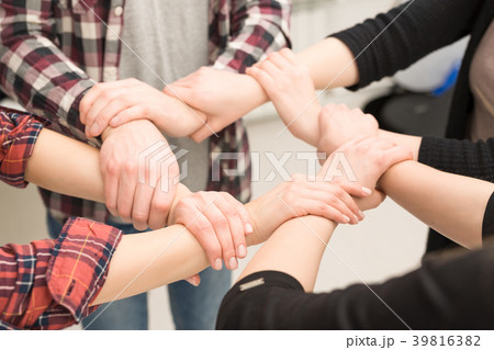A group of young people hold strong hands. 39816382