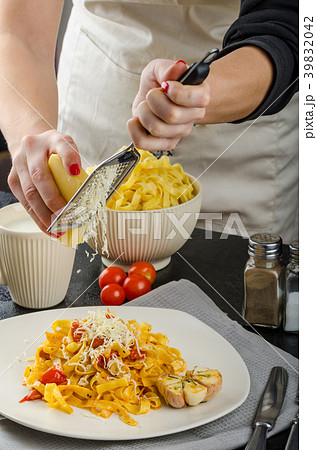 Chef prepares tagliatelle with garlic and cherry tomatoes 39832042