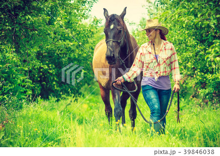 Western woman walking on green meadow with horse 39846038