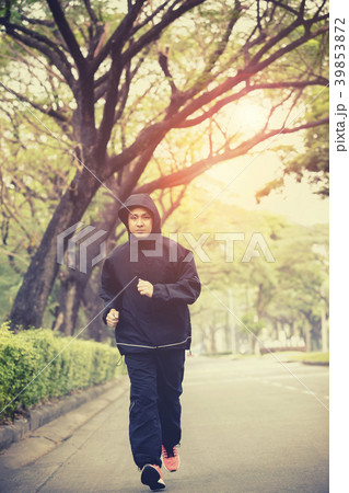 young man wearing hood jacket running on street 39853872
