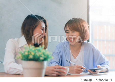 Two young business women sitting at table in cafe. Two young business women sitting at table in cafe. 39854814