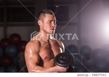 Muscular man working out in gym doing exercises 39857541