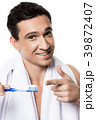 Handsome man with towel brushing his teeth.  39872407