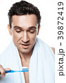 Handsome man with towel brushing his teeth.  39872419