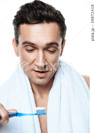 Handsome man with towel brushing his teeth.  39872419