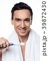 Handsome man with towel brushing his teeth.  39872430