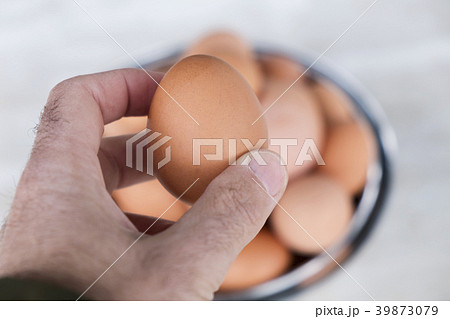 man with a brown egg in his hand 39873079
