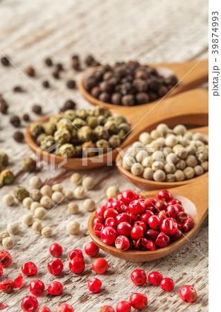Different pepper in a wooden spoons on wooden tabl 39874993