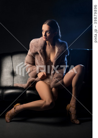 Pretty brunette in fur coat on a sofa in the dark Pretty brunette in fur coat on a sofa in the dark 39879896
