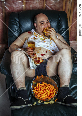 Overweight man eating and watching TV 39891720