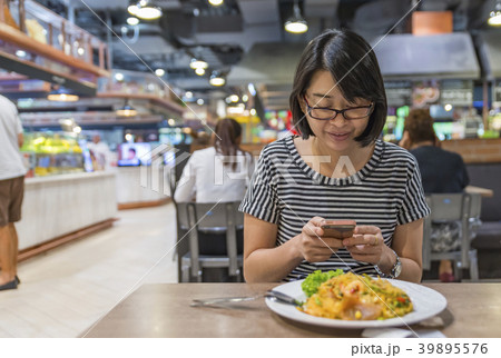 Asian woman using smart phone in food cafeteria 39895576