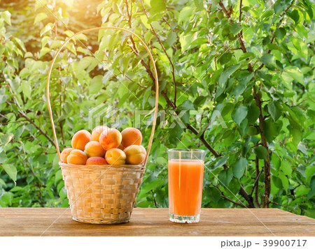 Apricots in a wicker basket and a glass of juice 39900717