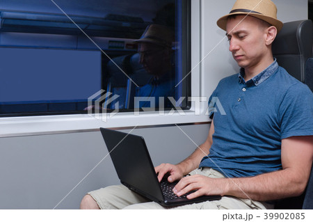 Young man in hat working behind a laptop sitting Young man in hat working behind a laptop sitting 39902085