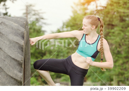 Girl in sportswear boxing with the tire 39902209