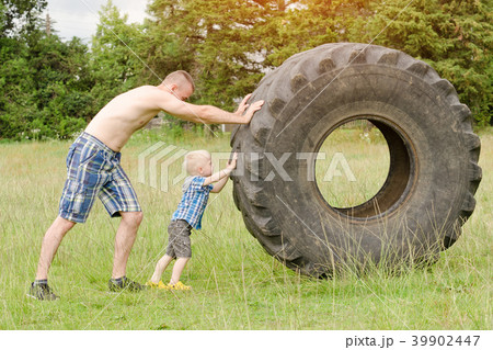 Dad and son push a big tire. Street workout 39902447