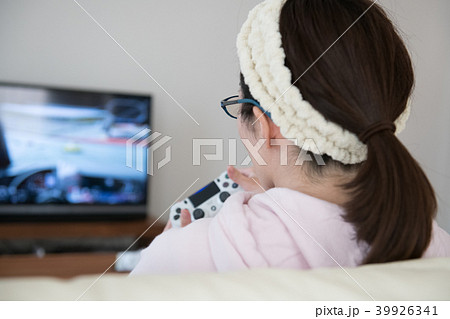 テレビゲームに熱中する若い日本人女性の後ろ姿の写真素材