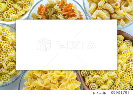 Macaroni ruote Different pasta in a glass and wooden bowl with pasta spirals on a white background Macaroni ruote Different pasta in a glass and wooden bowl with pasta spirals on a white background 39931792