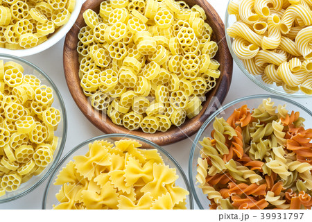 Macaroni ruote Different pasta in a glass and wooden bowl with spirals on a white background, close Macaroni ruote Different pasta in a glass and wooden bowl with spirals on a white background, close 39931797