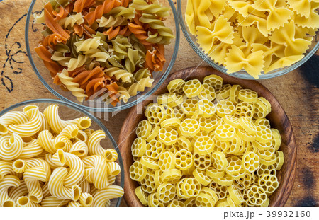 Macaroni ruote Different pasta in a glass and wooden bowl with pasta spirals on a decorated rustic 39932160