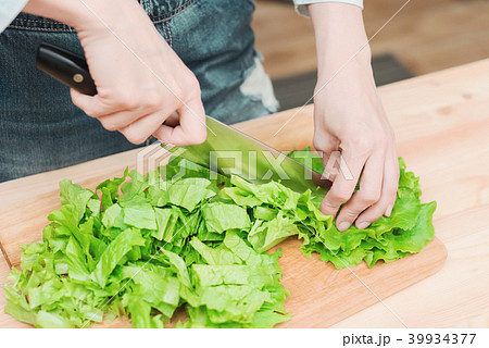 Close-up Female hands chopping a green plant salad cooking salad from vegetables on a wooden cutting Close-up Female hands chopping a green plant salad cooking salad from vegetables on a wooden cutting 39934377