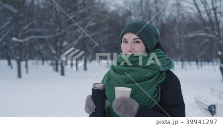 teenage girl pouring hot cocoa into paper cup in park on a winter day teenage girl pouring hot cocoa into paper cup in park on a winter day 39941297