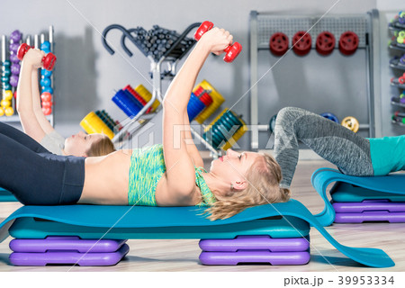 woman lifting dumbbells lying down woman lifting dumbbells lying down 39953334