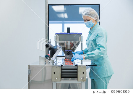 Pharmacy industry woman worker in protective clothing operating production of tablets in sterile Pharmacy industry woman worker in protective clothing operating production of tablets in sterile 39960809