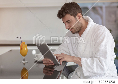 young freelancer in bathrobe working from home using tablet computer 39965658