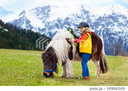 Kids riding pony. Child on horse in Alps mountains Kids riding pony. Child on horse in Alps mountains 39966369