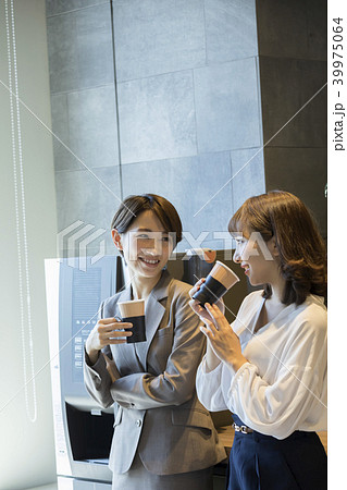 休憩スペースで寛ぐOLと自動販売機で飲み物を買うビジネスマン手元 39975064
