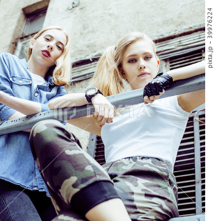 Two teenage girls infront of university building smiling, having 39976224