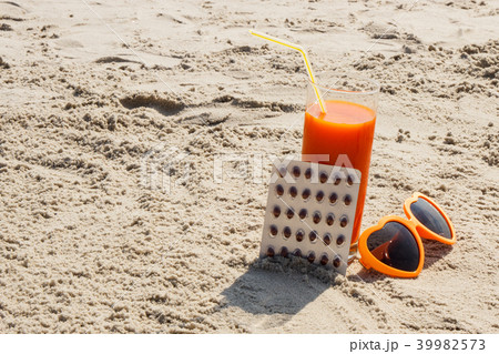 Medical pills, carrot juice and sunglasses on sand Medical pills, carrot juice and sunglasses on sand 39982573