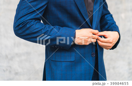 Man wear suit fixing button in front of the wall Man wear suit fixing button in front of the wall 39984655