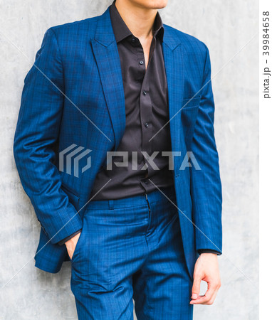 A man wearing a suit in front of a wall. A man wearing a suit in front of a wall. 39984658
