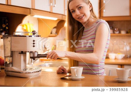 Woman in kitchen making coffee from machine Woman in kitchen making coffee from machine 39985928