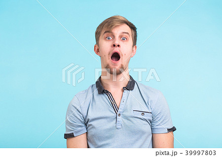 Closeup portrait of shocked stunned surprised young man eyes and mouth wide open on blue background 39997803