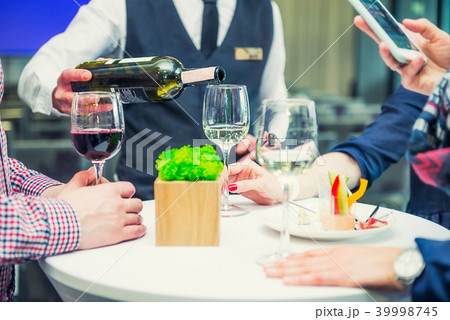 Professional waiter serving wine to guest 39998745