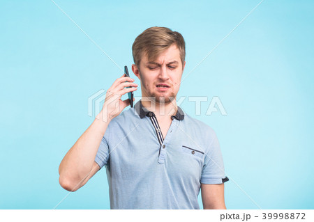 Handsome man with a tired and irritated look takes the phone away from her ear trying to move away Handsome man with a tired and irritated look takes the phone away from her ear trying to move away 39998872