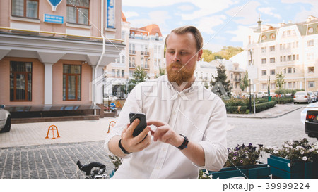 Portrait of handsome bearded man leaning on bicycle and using mobile phone 39999224