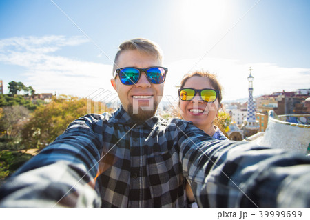 Travel couple happy talking selfie portrait with smartphone in Park Guell, Barcelona, Spain 39999699