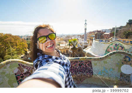 Young happy woman talking selfie portrait with smartphone in Park Guell, Barcelona, Spain. Beautiful 39999702