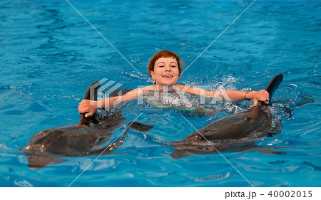 Young happy girl swimming with dolphin 40002015