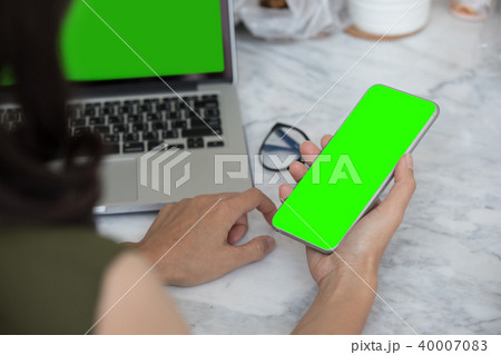 Close up woman hands using smartphone and laptop 40007083