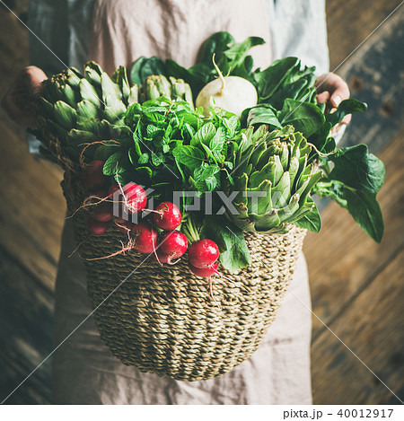 Female farmer holding basket of fresh garden vegetables, square crop 40012917