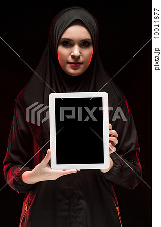 Portrait of beautiful smart young muslim woman wearing black hijab holding tablet in her hands as 40014877