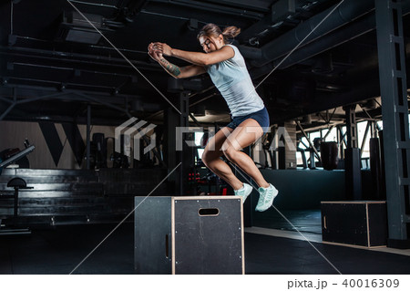 Sporty girl jumping over some boxes in gym 40016309